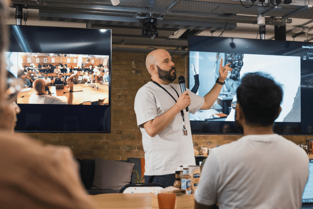 Uomo parla in una sala con tante persone ad ascoltarlo